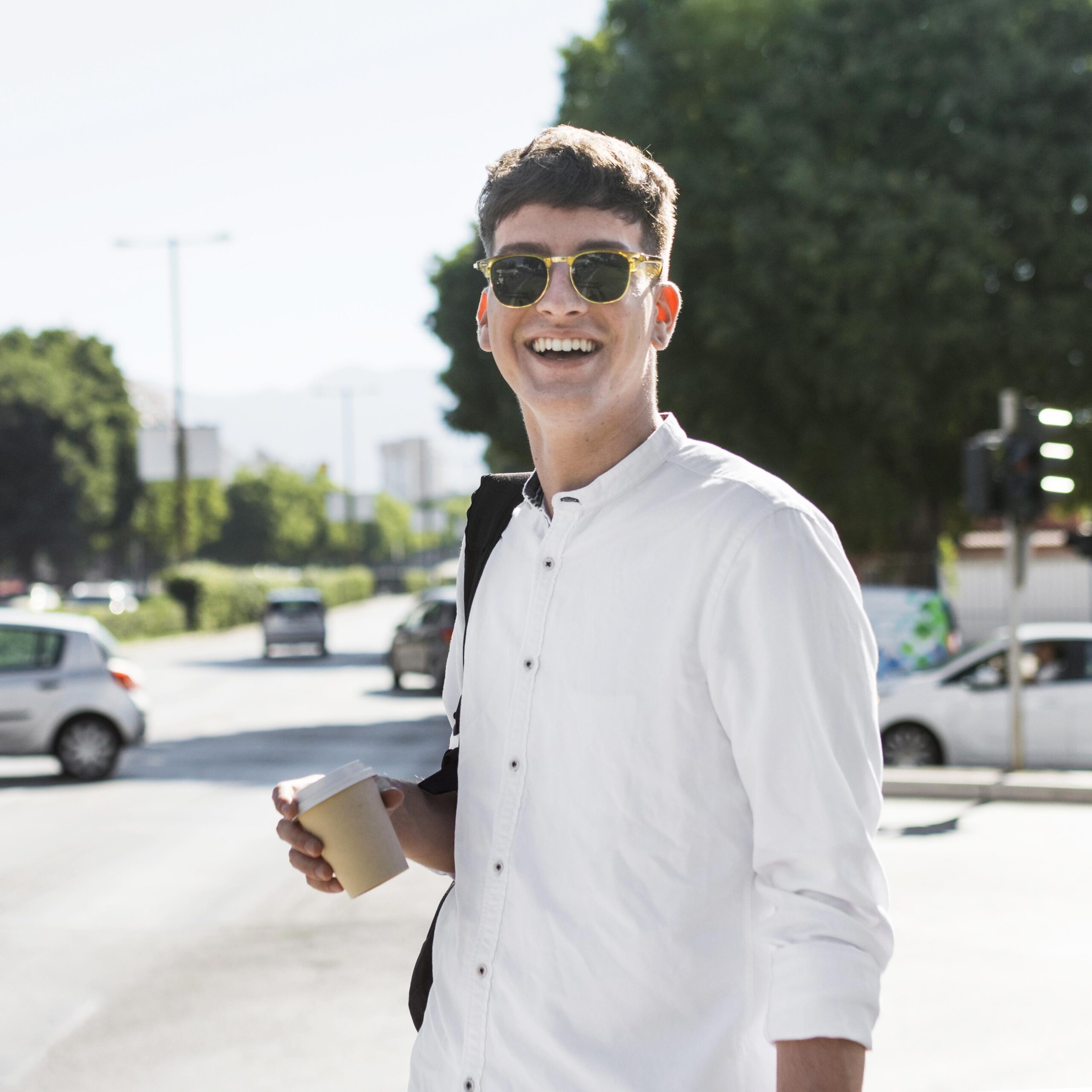 smiley-man-with-sunglasses-having-coffee-outdoors-city